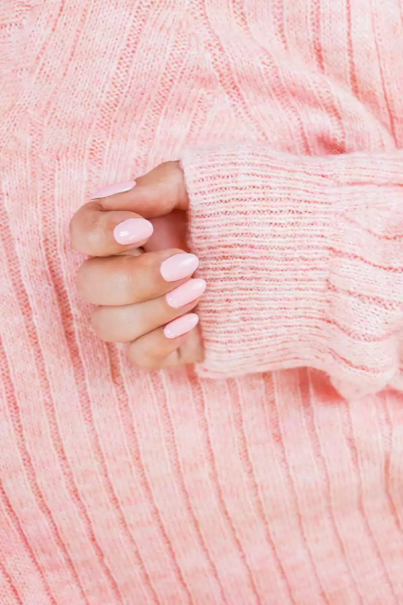 Rosa Maniküre auf der Textur eines rosa Pullovers